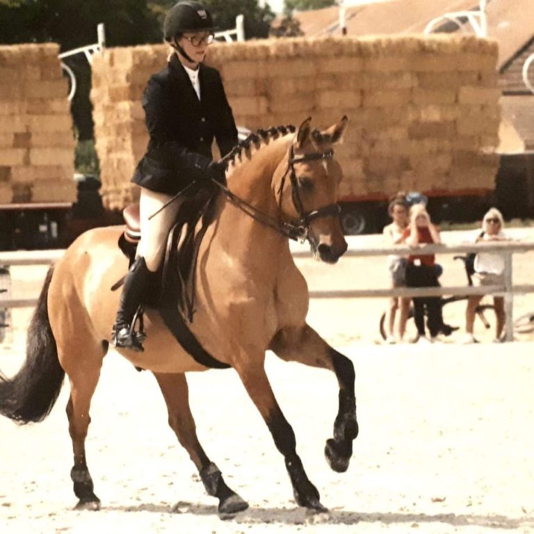 Cavaliere en tenue de concours montant un cheval sur un terrain équestre.
